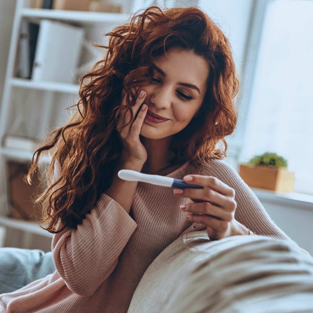 A smiling woman looking at a pregnancy test